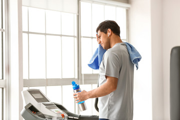 Young man resting after training on treadmill in gym
