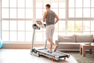 Young man training on treadmill at home