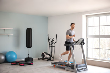 Young man training on treadmill in gym