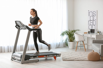 Fototapeta na wymiar Sporty young woman training on treadmill at home