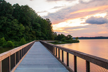 Greenway pedestrian bridge over lake with inspiring sunset