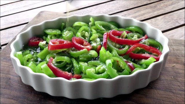 Green and red pepper salad on wooden background.