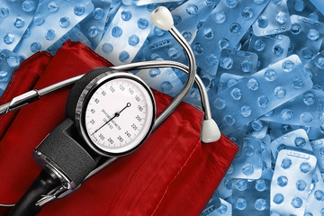 Classic tonometer against heap of empty pills blisters. Blood pressure monitoring tool, top view....