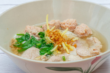 Thai Breakfast, Hot Thai rice soup with pork and meat on bowl with white wood background
