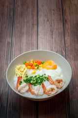 Delicious Thai HongKong Style Congee mixed with shrimp in the round bowl on the dark wood background. Thai, Hong Kong breakfast. 
