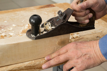 The hand holds the shirt and smooths the surface of the wooden bar. Carpentry workshop.
