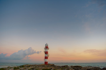 Lighthouse on a rocky shore in Cancun. Clear sky and blue sea. Mexico.