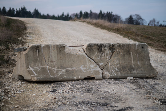 Damaged Concrete Barricade On Dirt Road