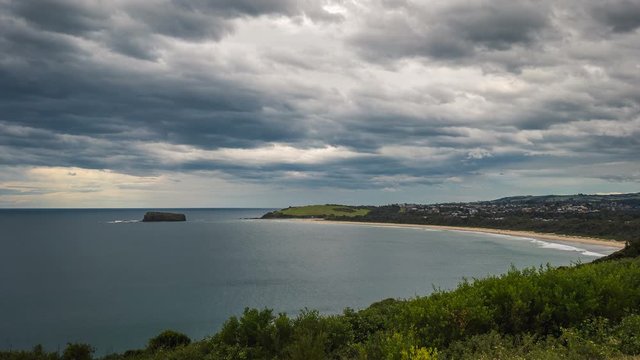 Time lapse of dark storm clouds moving over a small island next to an ocean bay on the south coast of Australia. 