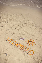 Medical pills, inscription vitamin D and shape of sun on sand at beach, summer time and healthy lifestyle