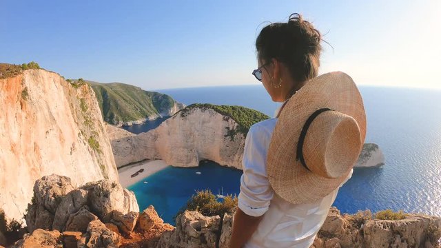 Young woman at Navagio Beach Shipwreck in Zante., taking pictures with vintage camera. Lagoon of Zakynthos island, Ionian Sea, Greece