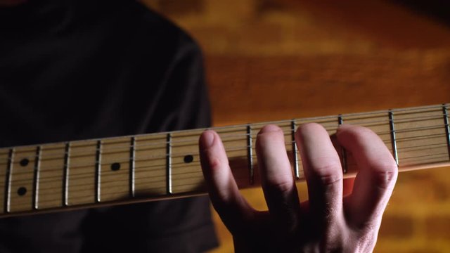 Male guitar player practices scale on electric guitar, close up on fretboard