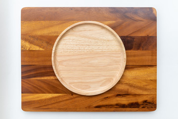 Round plates made of rubber wood with natural colors, polished and lacquered, placed on a wooden chopping block made of Chamchuri or mimosa trees with a white background.