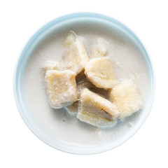 Banana in coconut milk on a vintage blue cup isolated on white background. Traditional sweet dessert of asian, Thailand.