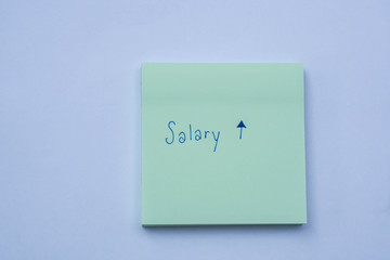 Business success concept sticky note with hand writing of salary increase and raise message