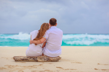 A man and a woman are sitting on the seashore and looking at the horizon.