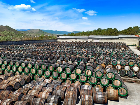 a lot of oak wine casks with madeira wine while maderization on solarium with mountain background. Crimea, Koktebel. Winery.