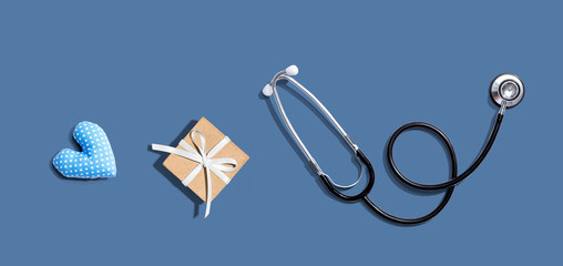 Stethoscope with a gift and a heart cushion - flat lay