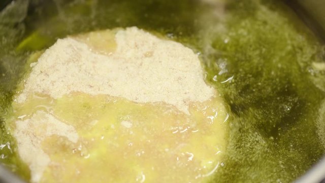 Chef's hands add a raw breaded seafood patty into the pan with hot oil, fishball frying with cod, flour, egg and breadcrumbs.