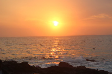 Beautiful blazing sunset landscape at black sea and orange sky above it with awesome sun golden reflection on calm waves as a background. Amazing summer sunset view on the beach. 