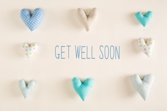 Get well soon message with blue heart cushions on a white paper background