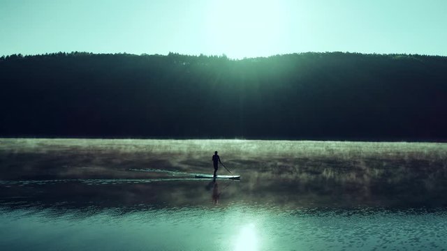 SUP in early morning sun with fog on lake