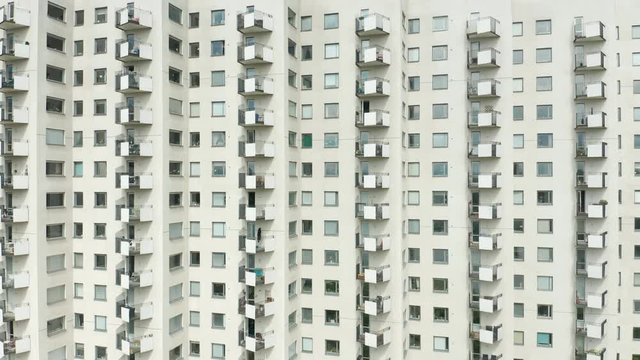 Exterior of a high rise multi story residentail apartment building - white facade, windows & balconies. Establishing shot aerial footage.