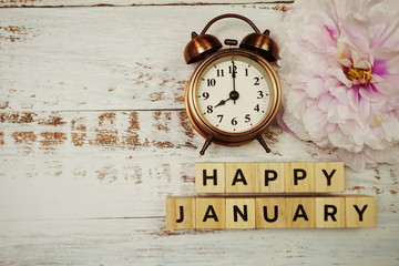 Happy January with alarm clock on wooden background