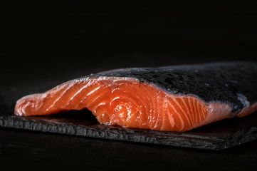 Raw salmon filet on dark slate background