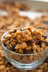 Healthy granola cereal with oats, pumpkin seeds, walnuts, and raisins in a glass bowl