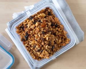 Healthy granola cereal with oats, pumpkin seeds, walnuts, and raisins in a plastic container