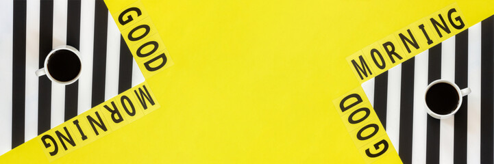 Text Good morning and cup of coffee on stylish black and white napkin on yellow background . Concept Flat lay Top view Copy space Banner