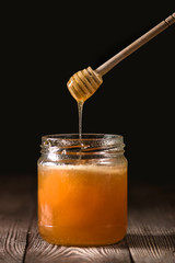 Honey with wooden honey dipper on wooden table