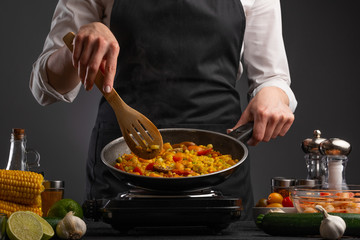 Cooking, the chef is fried in a pan of vegetables. A book of recipes and cooking, on a gray background