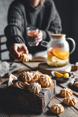 A woman reaches for a cake and drinks grapefruit tea. Healthy drink.