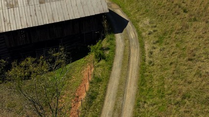 Top down shot of barn on a sunny day with the DJI Mavic2Pro drone. Top down of the path to the pasture where the cows walk. Farm land as farm as you can see with big and small cows. - Powered by Adobe