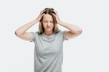 A young woman emotionally holds her hands behind her head with her eyes shut. Pain and stress....