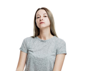 A young woman in a gray T-shirt is arrogantly looking at the camera. Selfishness. Isolated on a...