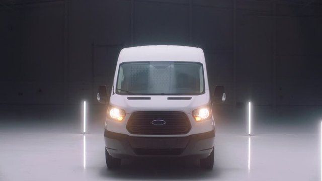 A white cargo van sits in an empty warehouse.