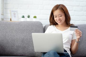 Beautiful young woman is happy to enjoy shopping online at home.