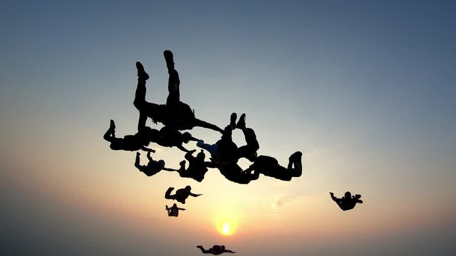 Silhouette of a group of skydivers jumping at the end of the day.