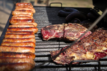 Delicious asado steak and chorizo roast on a parrilla barbecue grill in Argentina.