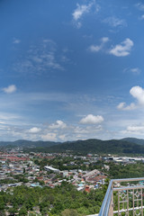 Obraz premium panoramic scene at Khao Rung Phuket viewpoint hilltop, home , building and green tree. Sea and mountain long distance, beautiful cloudy blue sky background at day time, nature and travel concept..