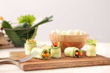 Board with tasty cucumber rolls on table