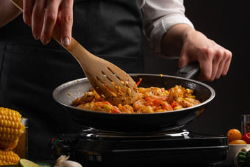 Frying seafood, shrimp with vegetables in a pan, on a gray background
