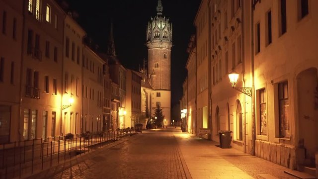 Tilt up to reveal the historic castle church in Wittenberg Germany at night, historic Martin Luther protestant reformer location.
