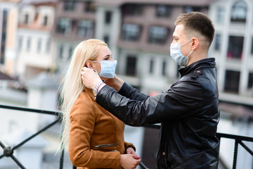 Young couple in love in protective medical mask on face outdoor at street. Environmental pollution concept. Guy and girl in virus protection