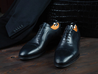 Black men's leather shoes on a background of a portfolio of crocodile leather and a jacket