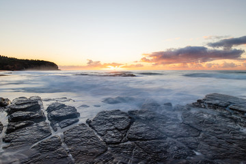 Water flowing over the rock texture at Turimetta Beach, Sydney, Australia during sunrise.