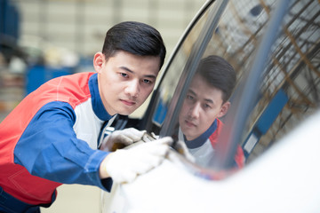 The mechanic checks the details of the car - the man holds the microfiber in the hand and polishes the car. Choose focus.